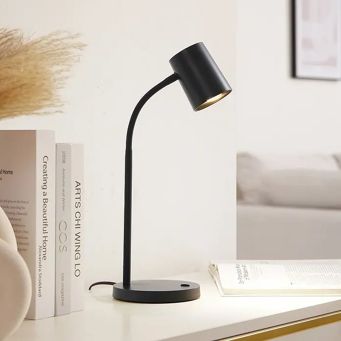 Lindby Tischleuchte Radka - L x B x H: 14,2 x 14,2 x 40,5 cm, schwarz, schwarz, GU10 - Schwarze, verstellbare Schreibtischlampe mit zylindrischem Kopf und rundem Fuß, beleuchtet einen Schreibtisch.