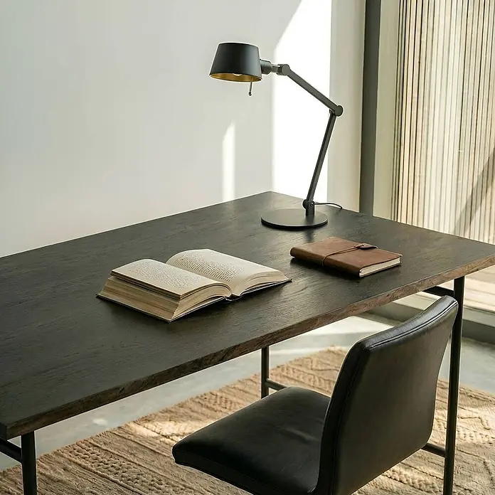 Lucande Tischleuchte Silka - schwarz, schwarz, E27 - Eine elegante schwarze Schreibtischlampe mit goldener Innenseite ruht auf einem dunklen Holzschreibtisch, bereit zum Lesen.