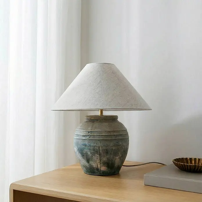 Lucande Tischleuchte Thalorin - braun / rost, E27 - Tischlampe mit blau-grauem Keramikfuß mit Rillen und hellem Stoffkegelschirm, auf einem Holztisch.