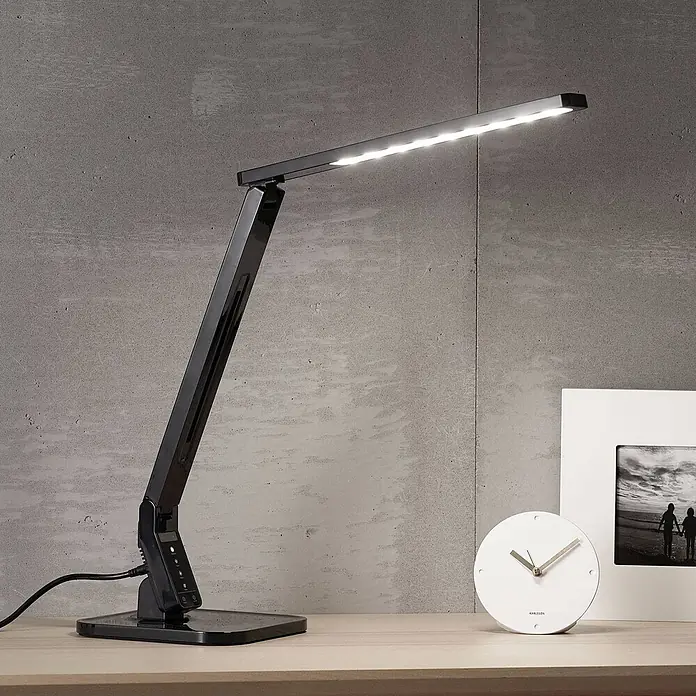 Lindby Tischleuchte Eleni - L x B x H: 18 x 17,2 x 45 cm, schwarz, schwarz - Eine elegante schwarze LED-Schreibtischlampe mit beleuchtetem Streifen an verstellbarem Arm auf hellem Holzschreibtisch.