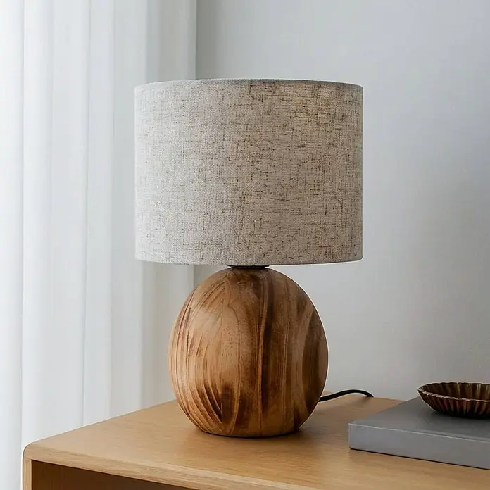 Lindby Tischleuchte Mayumi - L x B x H: 22 x 22 x 31 cm, Holz hell, alu / grau / zink, E27 - Moderne Tischlampe mit kugelförmigem Holzfuß und hellgrauem Stoffschirm auf einem hellen Holztisch.