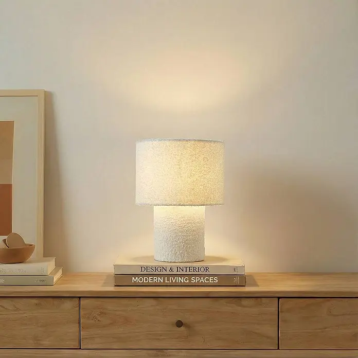 Lindby Tischleuchte Jone - L x B x H: 23 x 23 x 30 cm, weiß / opal, weiß / opal, E27 - Weiße texturierte Tischlampe auf Büchern, auf einer Holzkommode platziert.
