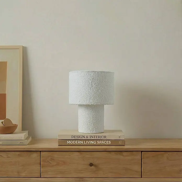 Lindby Tischleuchte Jone - L x B x H: 23 x 23 x 30 cm, weiß / opal, weiß / opal, E27 - Weiße, strukturierte Tischlampe mit zylindrischem Fuß und Schirm auf einer hellen Holzkommode neben Büchern.