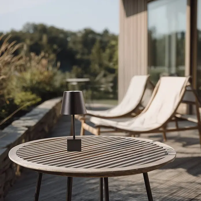 Lindby Tischleuchte Janea - L x B x H: 11,4 x 11,4 x 25 cm, schwarz, schwarz - Eine schwarze, tragbare Lampe mit quadratischem Sockel und konischem Schirm steht auf einem runden Latten-Holztisch.