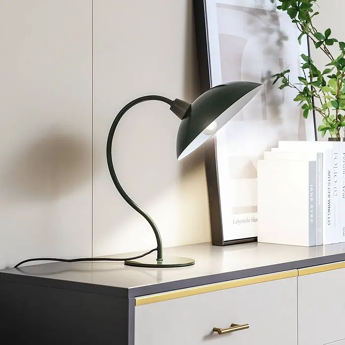 Lucande Tischleuchte Arvadon - grün, grün, E14 - Dunkelgrüne gebogene Tischlampe mit konischem Schirm, beleuchtet eine Oberfläche.