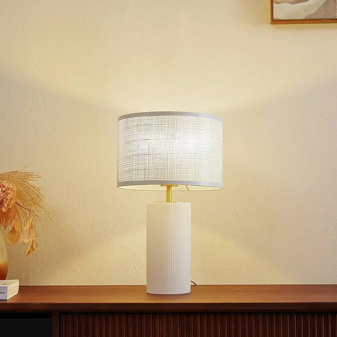 Lindby Tischleuchte Sorscha - L x B x H: 26 x 26 x 43 cm, weiß / opal, weiß / opal, E27 - Weiße geriffelte Tischlampe mit hellgrauem strukturiertem zylindrischem Schirm, beleuchtet auf Holzoberfläche.