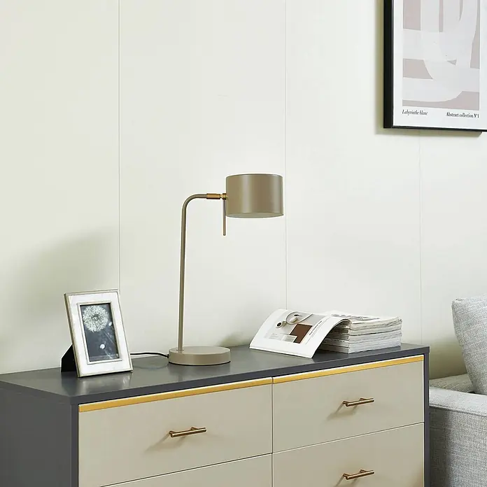 Lindby Tischleuchte Kaida - L x B x H: 30 x 15 x 43,5 cm, braun / rost, braun / rost, E27 - Matte taupe Schreibtischlampe mit Messingdetails, beleuchtet eine Kommode mit Bilderrahmen und Magazinen.