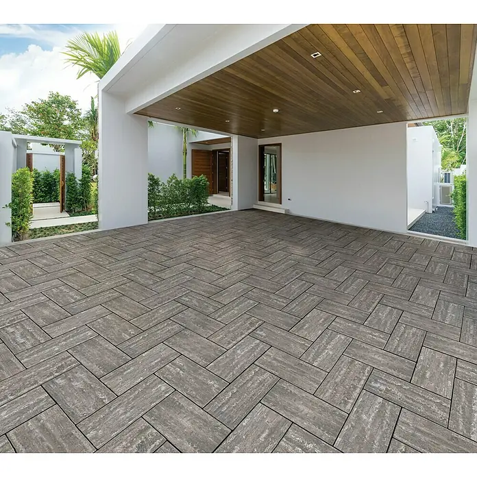 Terrassenplatte Latina - 48 x 24 x 3 cm, Mediterran, Beton - Eine stilvolle Einfahrt mit grauem Pflaster im Fischgrätmuster, das eine moderne und elegante Optik erzeugt. Die grauen Pflastersteine fügen sich nahtlos in die Architektur ein.