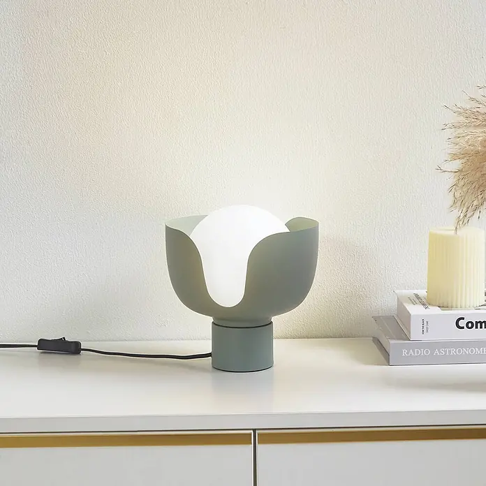 Lindby Tischlampe in grün, Nachttischlampe -  - Salbeigrüne Tischleuchte mit weißem Diffusor auf weißer Kommode, neben Büchern und einer Kerze.
