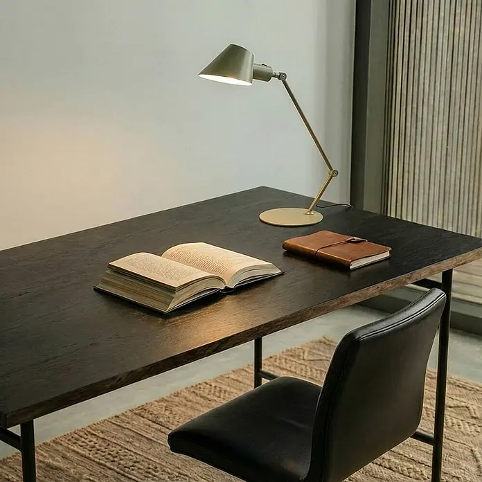 Lindby Tischleuchte Corali - grün, grün, E27 - Dunkler Holzschreibtisch mit verstellbarer Schreibtischlampe, offenem Buch und Notizbuch. Ein schwarzer Lederstuhl steht davor.
