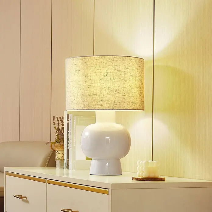Lindby Tischleuchte Arved - L x B x H: 30 x 30 x 46 cm, weiß / opal, weiß / opal, E27 - Weiße Keramik-Tischlampe mit beigem Leinenschirm, spendet warmes Licht auf einer Kommode.