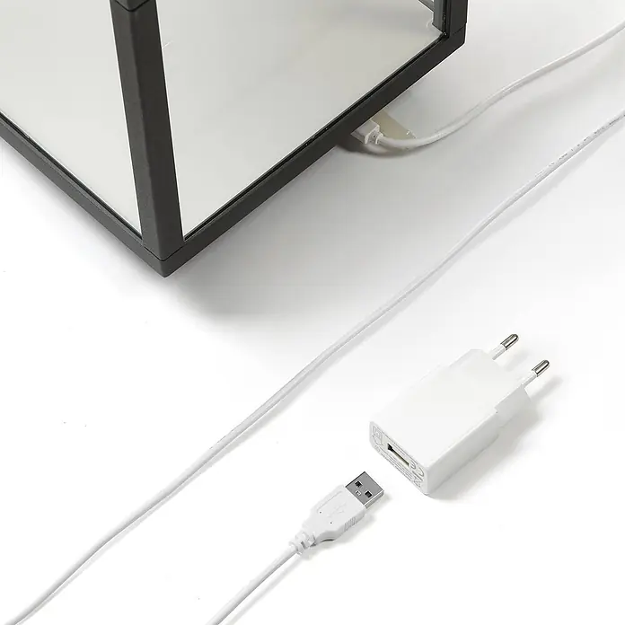 Lucande Tischleuchte Cube - schwarz - Weißes USB-Ladekabel und EU-Netzteil an einem schwarz gerahmten Gerät.