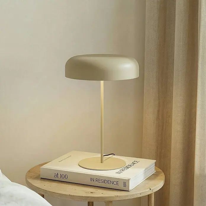 Lindby Tischleuchte Edion - braun / rost, braun / rost, E14 - Moderne, hellbeige Tischleuchte mit abgerundetem Schirm auf einem Holztisch neben einem Bett.