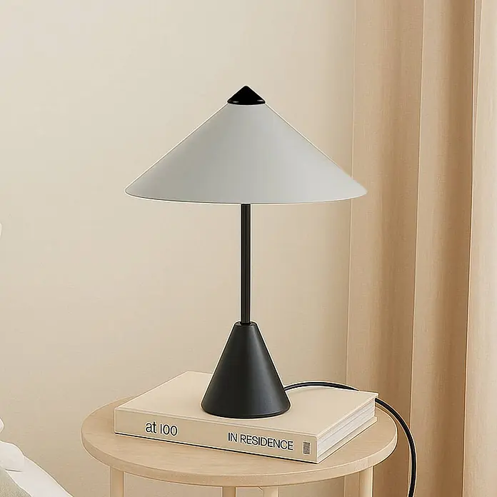 Lindby Tischleuchte Norvik - L x B x H: 27 x 27 x 35,8 cm, schwarz, alu / grau / zink, G9 - Tischlampe mit schwarzem konischem Sockel, Stiel und hellgrauem konischem Schirm auf einem Holztisch neben einem Buch.