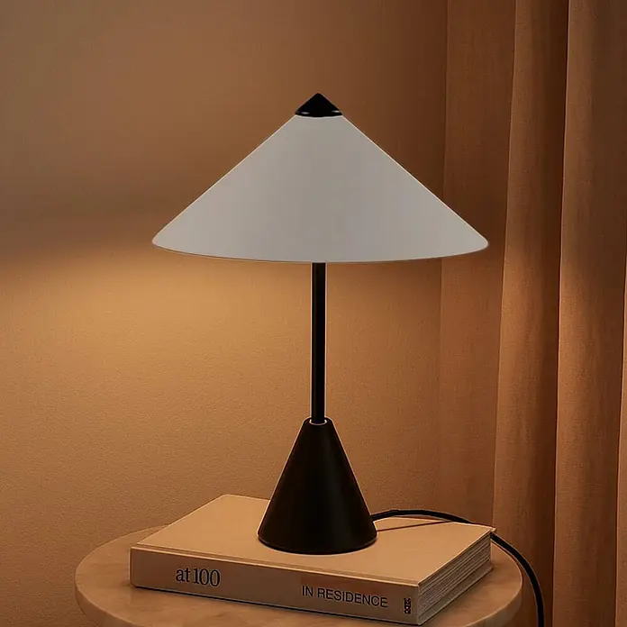 Lindby Tischleuchte Norvik - L x B x H: 27 x 27 x 35,8 cm, schwarz, alu / grau / zink, G9 - Tischlampe mit konischem weißem Schirm und schwarzem Fuß, beleuchtet ein Buch auf einem Beistelltisch.