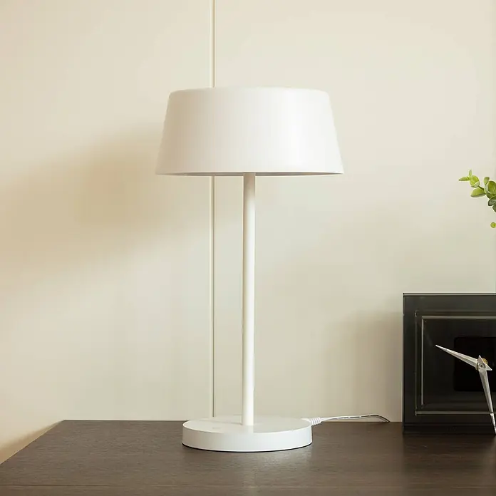 Lindby Tischleuchte Milica - L x B x H: 18,3 x 18,3 x 33,6 cm, weiß / opal, weiß / opal - Weiße Tischlampe mit konischem Schirm und zylindrischem Sockel auf einer dunklen Holzoberfläche.
