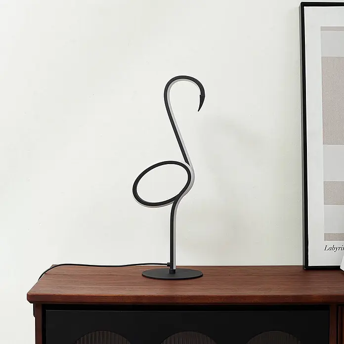 Lindby Tischleuchte Pajaro - L x B x H: 18 x 2,4 x 49,5 cm, schwarz, schwarz - Minimalistische schwarz-weiße LED-Tischlampe in abstrakter Flamingoform auf dunkler Holzoberfläche.