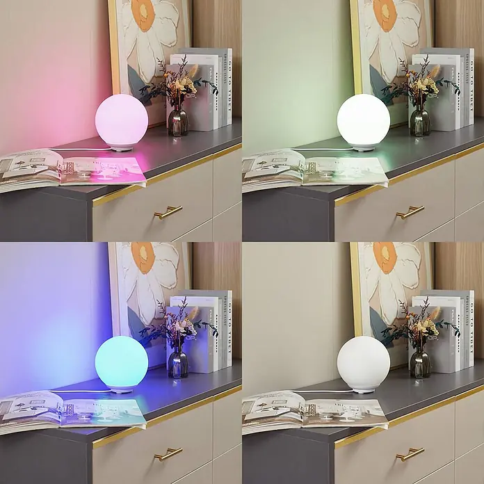 Lindby Tischleuchte Cosmia - L x B x H: 15 x 15 x 15,7 cm, weiß / opal - Eine kugelförmige LED-Lampe zeigt verschiedene Farben (Pink, Grün, Blau, Weiß) auf einem Schrank.