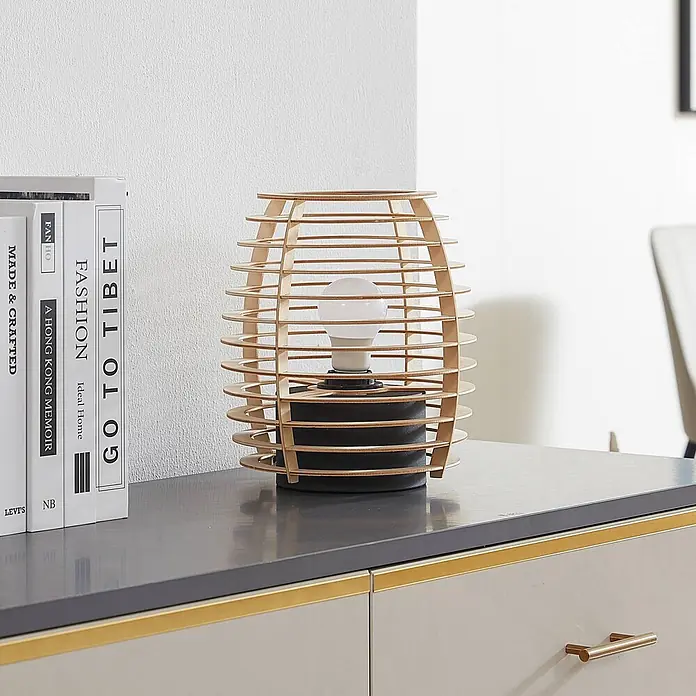Lindby Tischleuchte Ediz - L x B x H: 22 x 22 x 25 cm, Holz hell, E27 - Tischlampe mit Holzlamellenschirm und schwarzem Fuß, auf einem grauen Tisch neben Büchern.