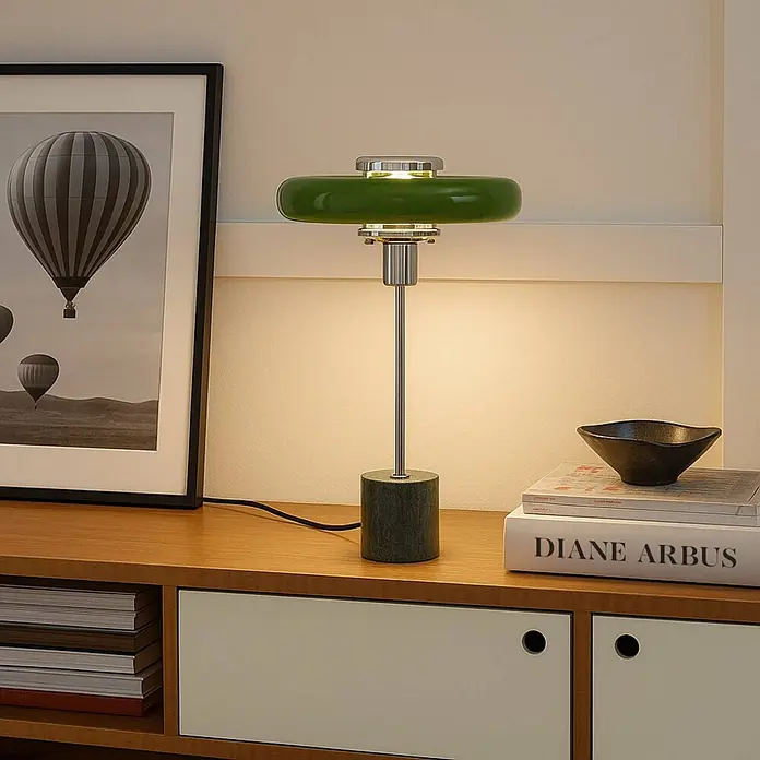 Lindby Tischleuchte Branford - L x B x H: 25 x 25 x 46 cm, grün, grün, E14 - Grüne Tischlampe mit Metallschaft und zylindrischem Sockel, die Licht auf einem Holzschrank spendet.