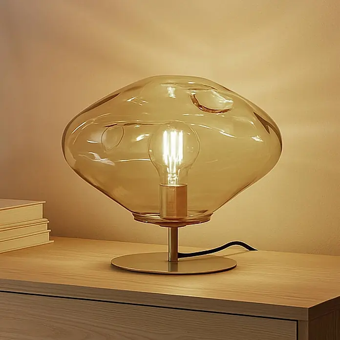 Lindby Tischleuchte Lelia - L x B x H: 35 x 35 x 27,5 cm, creme / amber, E27 - Tischlampe aus amberfarbenem Glas mit sichtbarer Glühbirne auf Holzoberfläche.