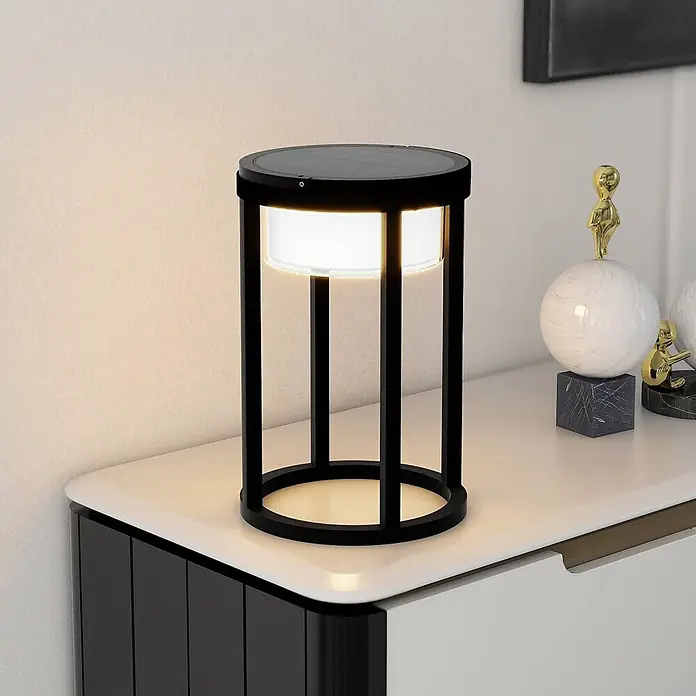 Lucande Tischleuchte Tilena - L x B x H: 21 x 21 x 32 cm, schwarz - Schwarze zylindrische Solarlampe mit leuchtendem Diffusor, auf einem Schrank ausgestellt.