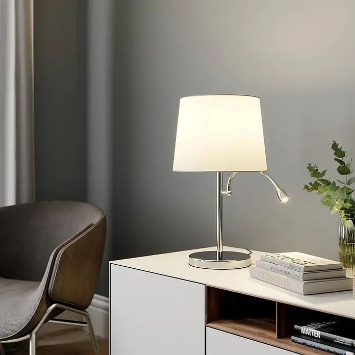 Lindby Tischleuchte Benjiro - L x B x H: 30 x 30 x 52,5 cm, chrom / silber, weiß / opal, E27 - Tischleuchte aus Chrom mit weißem Schirm und flexiblem LED-Leselicht, auf Sideboard neben Büchern.