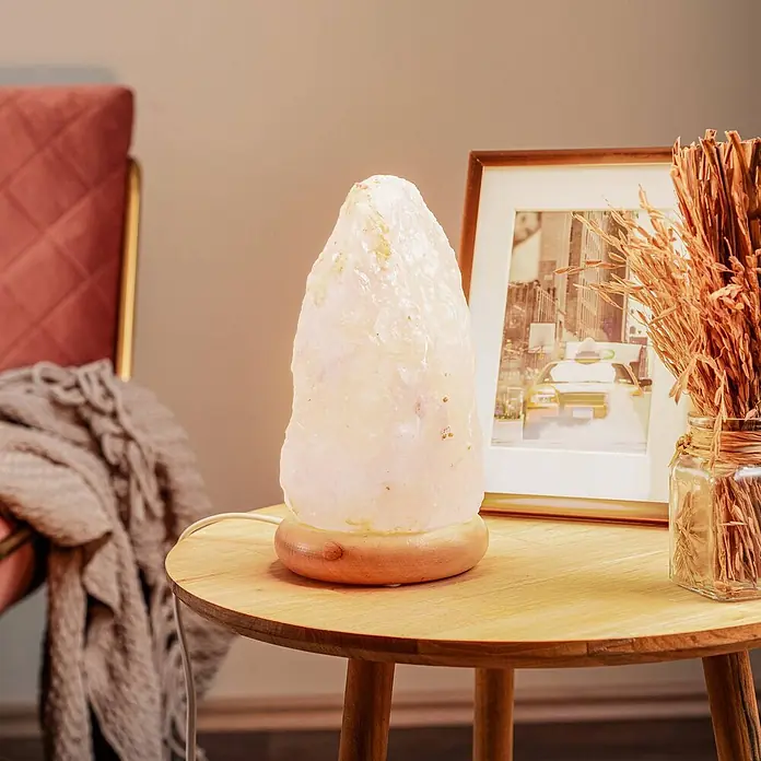 Envostar Tischleuchte Harmony - rot, E14 - Eine leuchtende Himalaya-Salzlampe mit unregelmäßiger, kristalliner Form und rundem Holzsockel, die ein sanftes, warmes Licht auf einen Holztisch wirft.
