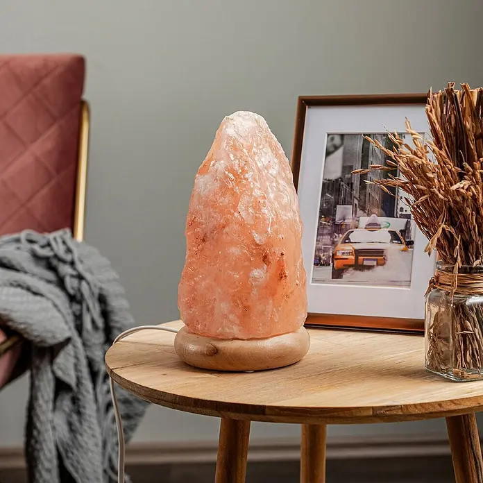 Envostar Tischleuchte Harmony - rot, E14 - Rosa-orange Himalaya-Salzlampe mit Holzsockel auf einem Beistelltisch aus Holz.