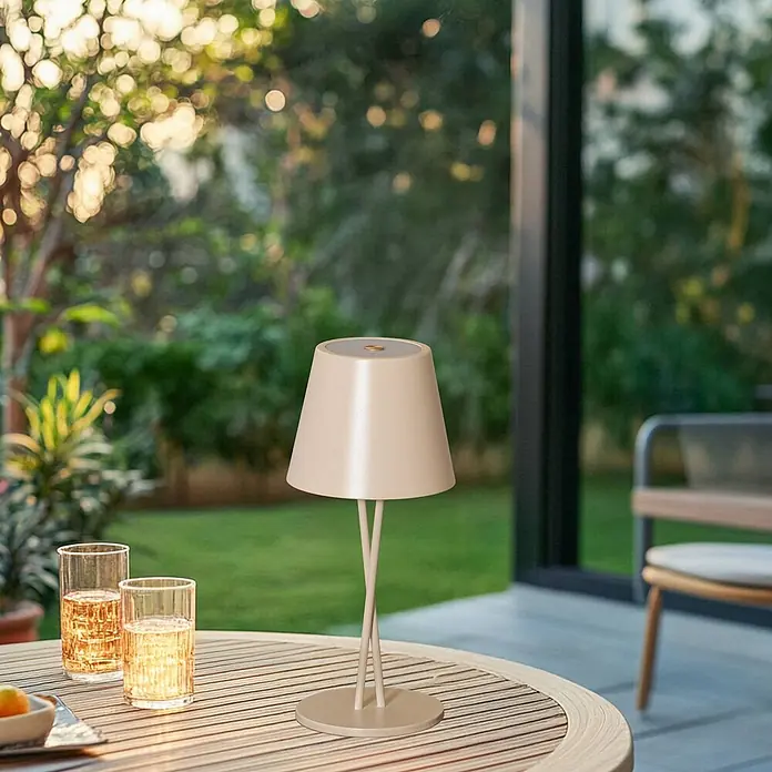 Lindby Tischleuchte Janea - creme / amber, creme / amber - Beige kabellose Outdoor-Tischlampe auf einem Lattenholztisch mit Getränken.