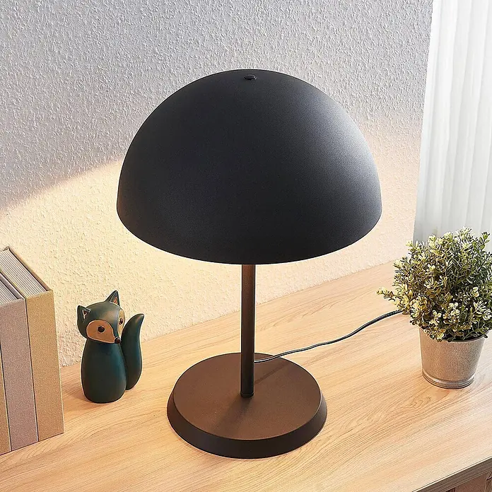 Lindby Tischleuchte Idalene - L x B x H: 35 x 35 x 51 cm, schwarz, schwarz, E27 - Schwarze kuppelförmige Tischleuchte auf einem Holzschreibtisch, spendet warmes Licht, neben Büchern und einer Deko-Fuchsfigur.