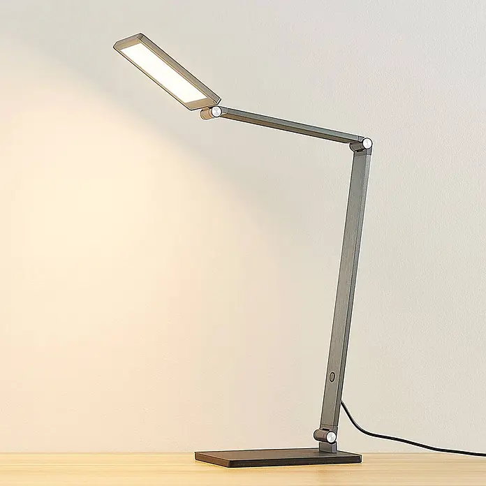 Lucande Tischleuchte Mion - L x B x H: 36,5 x 12 x 41 cm, alu / grau / zink, alu / grau / zink - Moderne graue, verstellbare LED-Schreibtischlampe beleuchtet eine Holzoberfläche.