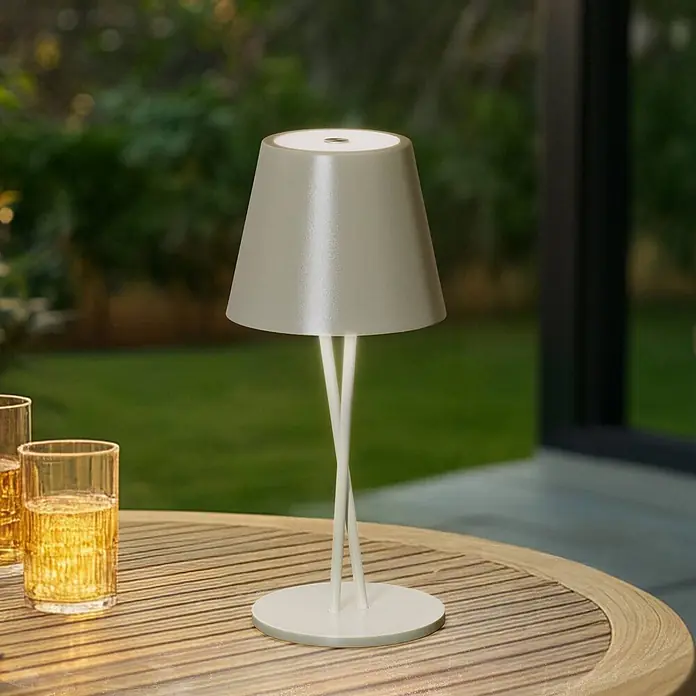 Lindby Tischleuchte Janea - L x B x H: 11,4 x 11,4 x 25 cm, grün, grün - Hellgraue tragbare Tischleuchte mit konischem Schirm und gedrehtem Fuß, auf einem Outdoor-Holztisch.