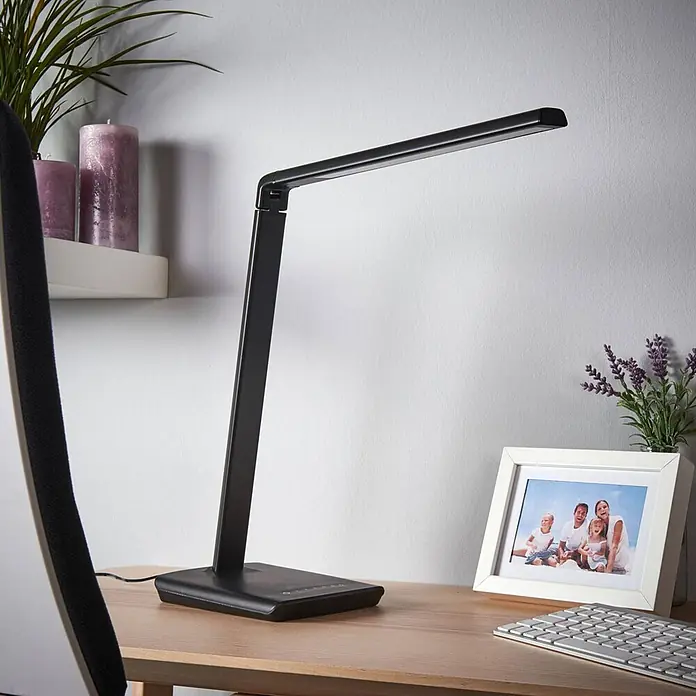 Lindby Tischleuchte Kuno - L x B x H: 37,6 x 15,8 x 46 cm, schwarz, schwarz - Eine schlanke, schwarze Schreibtischlampe mit verstellbarem Arm steht auf einem Holzschreibtisch.