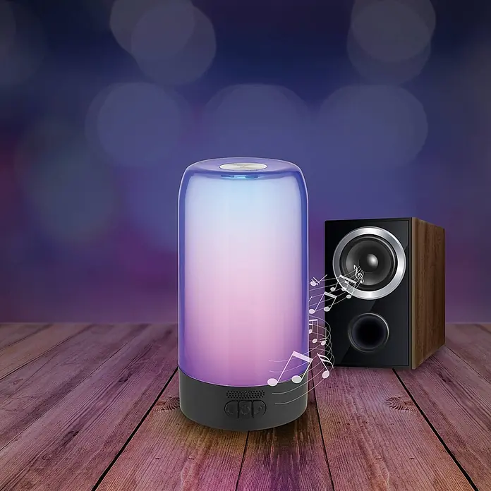 Prios Tischleuchte Valtari - L x B x H: 10 x 10 x 18,8 cm, schwarz, klar / transparent - Zylindrische farbwechselnde Lampe mit dunklem Sockel und Lautsprecher auf Holztisch, sendet Licht und Musiknoten aus.