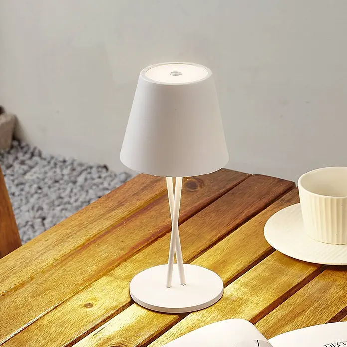 Lindby Tischleuchte Janea - weiß / opal, weiß / opal - Weiße konische Tischlampe mit gekreuztem Stiel und rundem Fuß, leuchtend auf einem Holztisch.