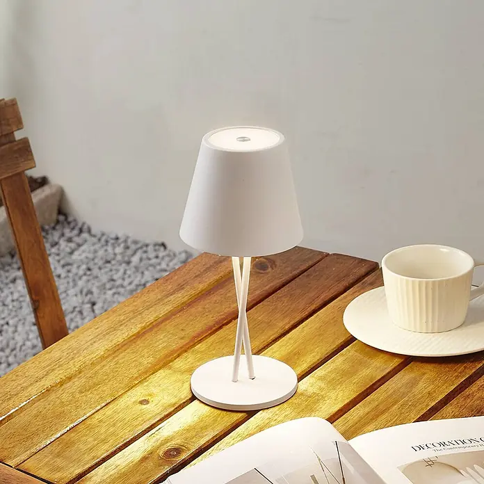 Lindby Tischleuchte Janea - weiß / opal, weiß / opal - Weiße moderne Tischleuchte, beleuchtet, auf einem Holztisch im Freien.