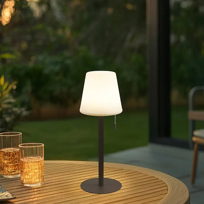 Lindby Tischleuchte Azalea - L x B x H: 16,5 x 16,5 x 45 cm, braun / rost - Beleuchtete weiße Tischlampe mit dunklem Fuß auf einem Holz-Gartentisch.