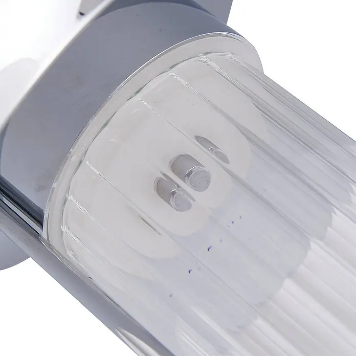 Lindby Tischleuchte Mareli - klar / transparent, chrom / silber - Nahaufnahme einer verchromten Leuchte mit klarem, geripptem Zylinderdiffusor und zwei Metallstiften.