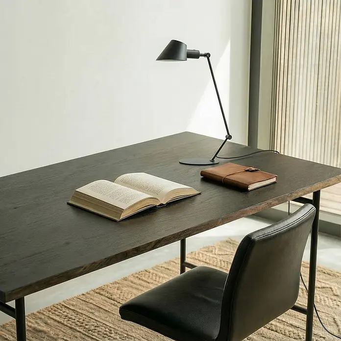 Lindby Tischleuchte Corali - schwarz, schwarz, E27 - Dunkler Holzschreibtisch mit eleganter schwarzer Schreibtischlampe, offenem Buch und braunem Notizbuch im Home Office.