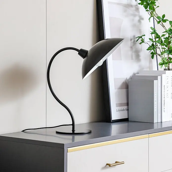 Lucande Tischleuchte Arvadon - L x B x H: 33 x 25 x 42,75 cm, schwarz, schwarz, E14 - Eine schwarze Metall-Schreibtischlampe mit gebogenem Stiel und schalenförmigem Schirm steht auf einer dunkelgrauen Oberfläche.