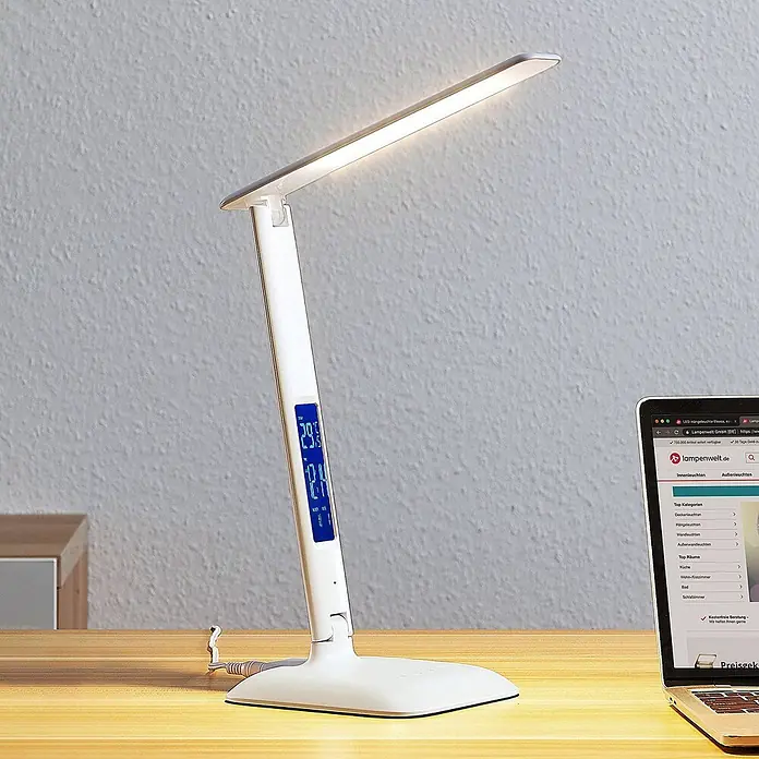 Lindby Tischleuchte Ludmilla - L x B x H: 26 x 15 x 34 cm, weiß / opal, weiß / opal - Weiße LED-Schreibtischlampe mit Digitalanzeige für Uhrzeit, Datum und Temperatur, beleuchtet einen Holzschreibtisch neben einem Laptop.