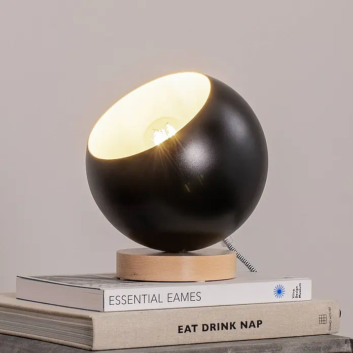 Envostar Tischleuchte Arvid - L x B x H: 17 x 17 x 19 cm, schwarz, E27 - Schwarze kugelförmige Tischlampe mit beleuchteter Glühbirne und Holzsockel, auf Büchern stehend.