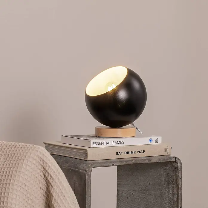 Envostar Tischleuchte Arvid - L x B x H: 17 x 17 x 19 cm, schwarz, E27 - Schwarze kugelförmige Tischleuchte mit Holzsockel und warmem Licht, auf Büchern stehend.