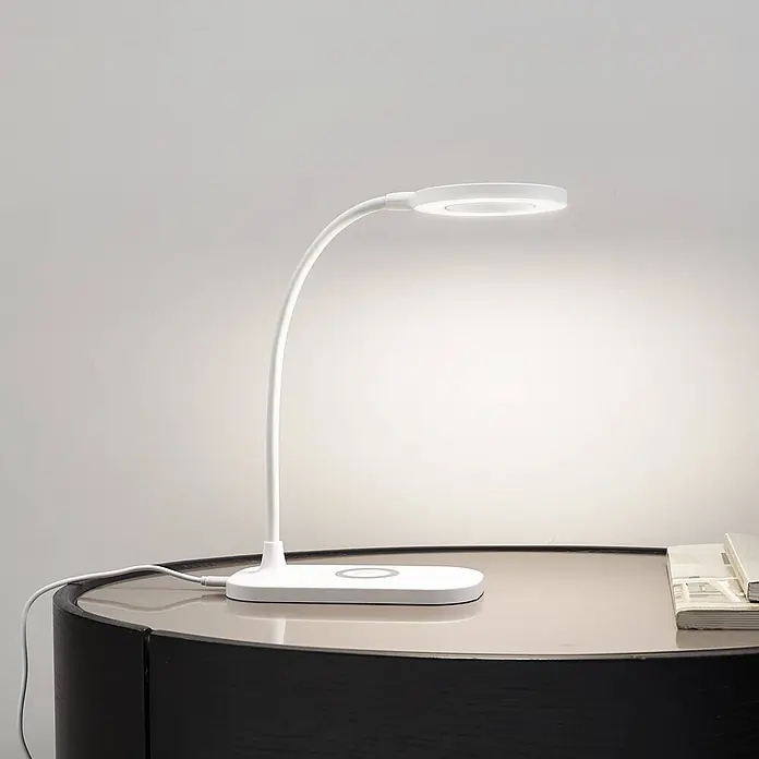 Lindby Tischleuchte Siona - weiß / opal, weiß / opal - Weiße LED-Schreibtischlampe mit flexiblem Schwanenhals und rundem Kopf, Basis mit integriertem kabellosen Ladepad, auf einem Tisch.
