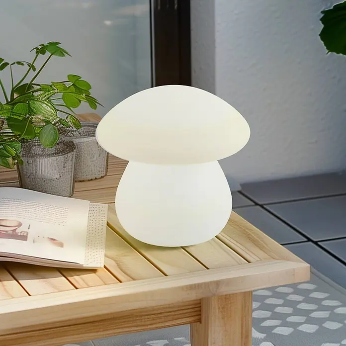 Lindby Tischleuchte Vernate - weiß / opal, weiß / opal - Pilzförmige opake weiße Tischlampe auf einem Holztisch in einer Outdoor-Umgebung.