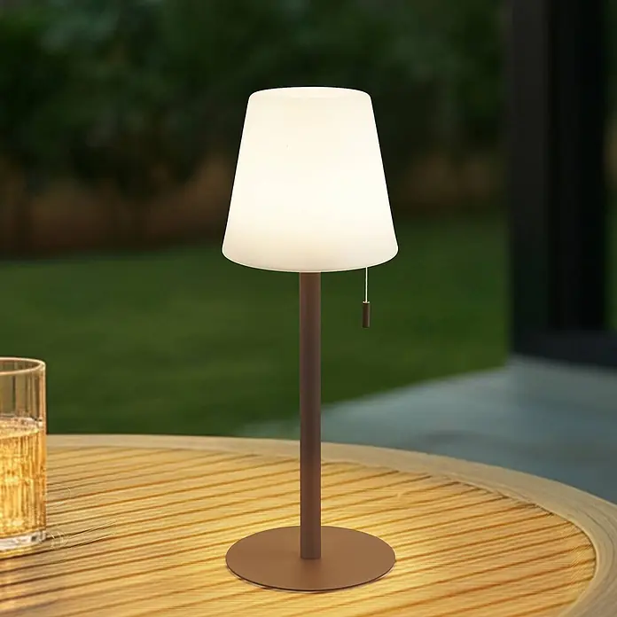 Lindby Tischleuchte Azalea - L x B x H: 16,5 x 16,5 x 45 cm, schwarz - Outdoor-Tischlampe mit leuchtendem weißem Schirm und braunem Ständer auf einem Holztisch.