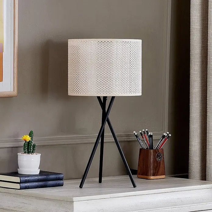 Lindby Tischleuchte Soula - L x B x H: 26 x 26 x 52 cm, schwarz, creme / amber, E27 - Eine Tischlampe mit hell geflochtenem zylindrischem Schirm und schwarzem Stativfuß, auf einem Schreibtisch neben Büchern und Stifthalter.