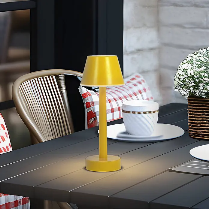 Lindby Tischleuchte Gaja - L x B x H: 9,5 x 9,5 x 24 cm, gelb / orange, gelb / orange - Eine hellgelbe kabellose Tischlampe beleuchtet einen dunklen Außentisch und zeigt ihr tragbares Design.