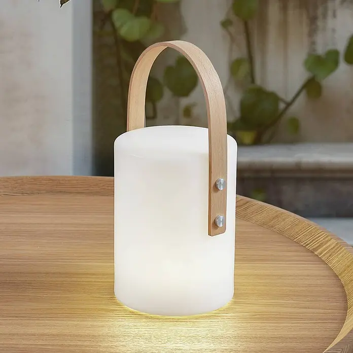 Lindby Tischleuchte Juria - L x B x H: 16,5 x 16,5 x 35,5 cm, weiß / opal - Weiße zylindrische Handleuchte mit Holzgriff und Metallnieten, sanft leuchtend auf einem Holztisch im Freien.